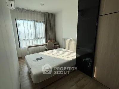 Modern bedroom with large window and stylish furniture in a cozy apartment.