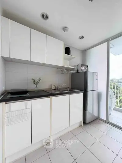 Modern kitchen with sleek white cabinets and stainless steel appliances in a bright apartment.