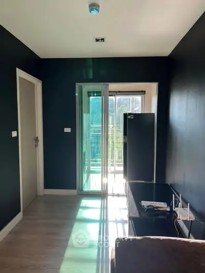 Modern living room with sleek black walls and sliding glass doors leading to a balcony.