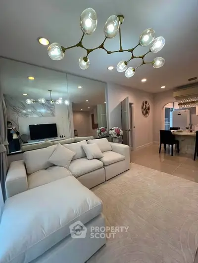 Luxurious living room with modern chandelier and plush white sofa in elegant apartment.