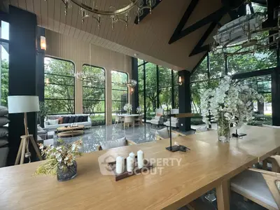 Luxurious modern living room with large windows and elegant decor, surrounded by lush greenery.