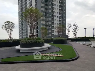 Modern high-rise building with landscaped garden and outdoor seating area.