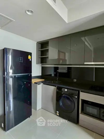Modern kitchen with sleek appliances and glossy cabinets in a contemporary apartment.