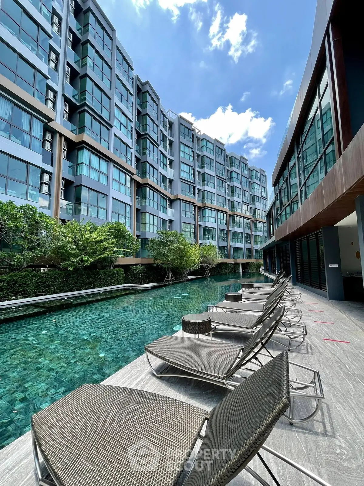 Luxurious poolside view at modern condominium with sleek architecture and sunny skies.