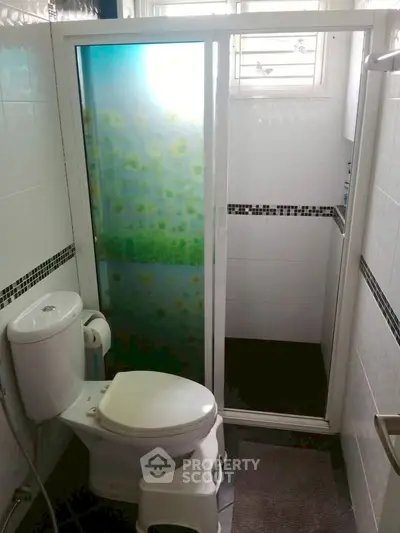 Compact bathroom with modern shower and toilet in a cozy apartment.