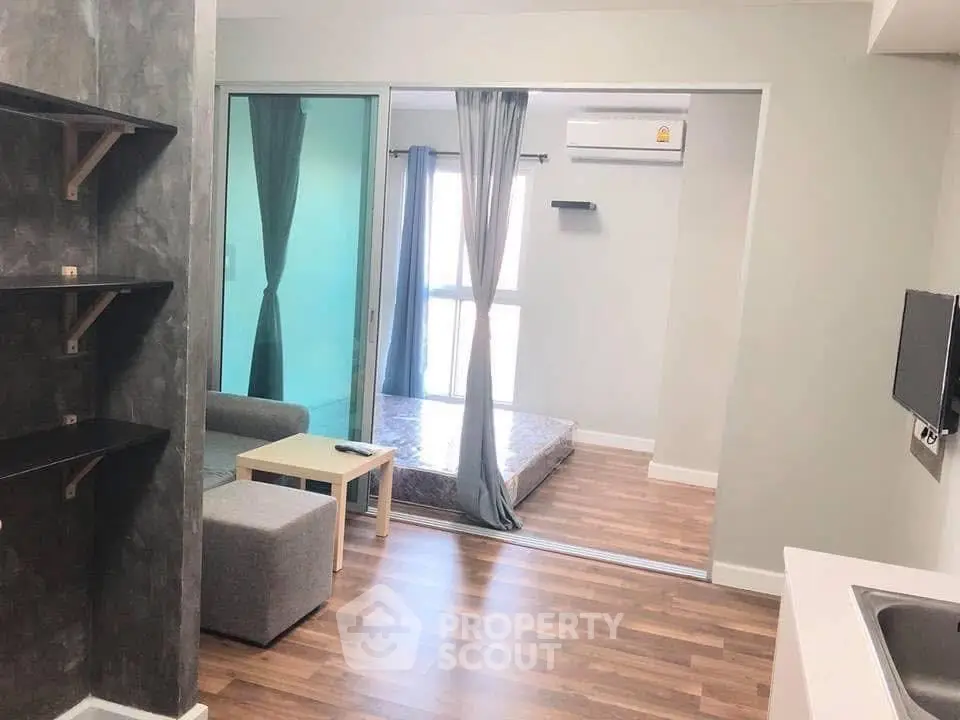 Modern apartment interior with open layout, featuring a cozy living area and bedroom separated by glass doors.