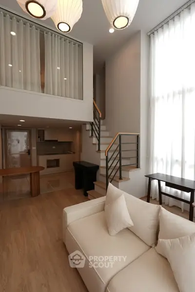 Luxurious modern living room with high ceilings and elegant staircase in a stylish duplex apartment.