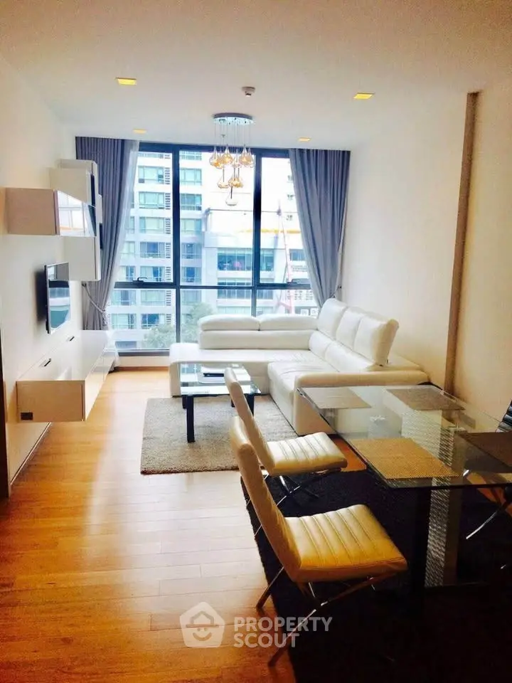 Modern living room with large windows and stylish furniture in a high-rise apartment.