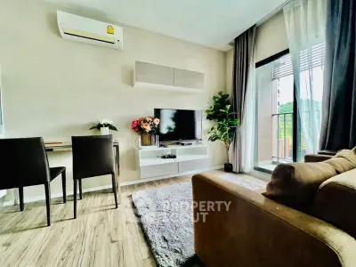 Modern living room with cozy seating, TV, and large window offering natural light.