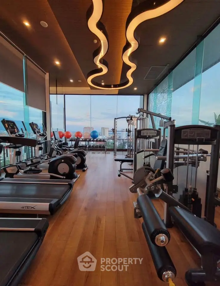 Luxurious gym with modern equipment and stunning city view in high-rise building.
