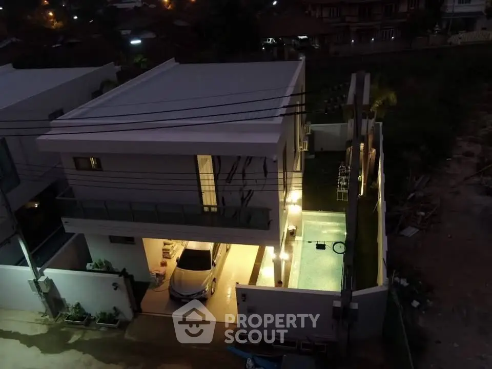 Stunning modern home with illuminated pool and spacious garage at night.