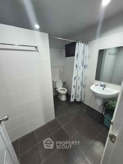 Modern bathroom with tiled walls and floor, featuring a shower curtain and sleek fixtures.