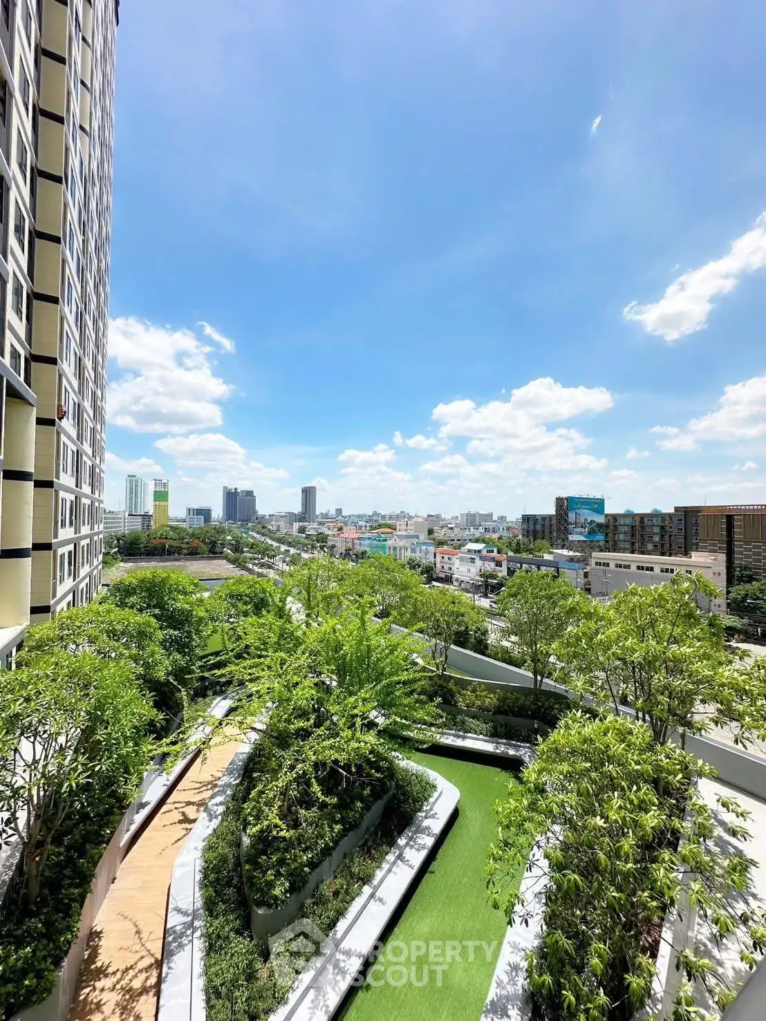 Stunning city view from high-rise building with lush green garden terrace.