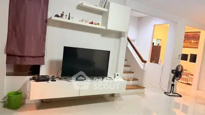 Modern living room with sleek TV setup and elegant staircase in stylish home