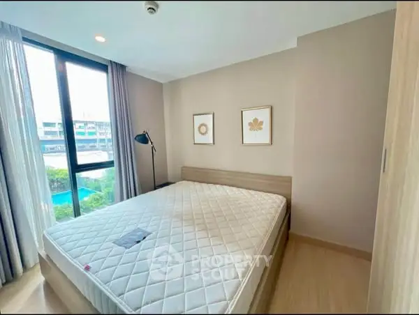 Modern bedroom with large window and minimalist decor in a high-rise apartment.
