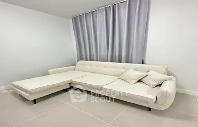 Spacious and modern living room with a large, comfortable white sectional sofa and elegant grey curtains, perfect for relaxation and entertaining guests.