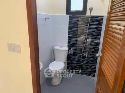 Compact bathroom with modern shower and toilet in a cozy real estate property.