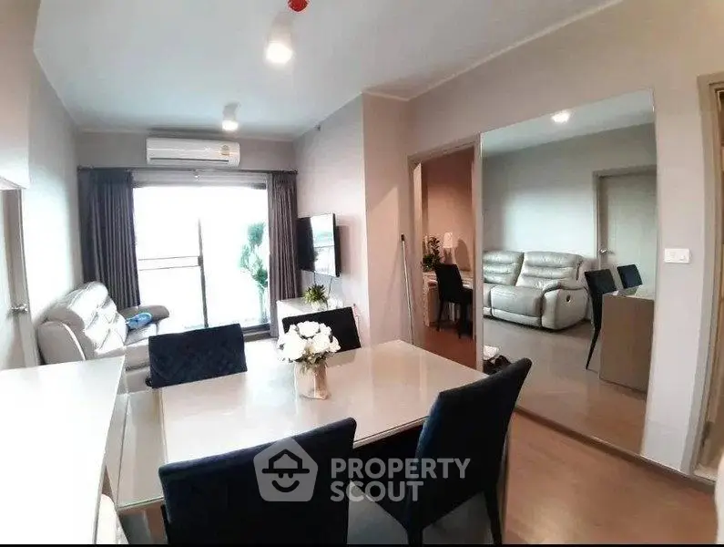 Modern living room with dining area and large mirror, featuring sleek furniture and bright lighting.