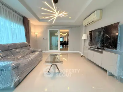 Modern living room with stylish lighting, sleek furniture, and large TV setup.