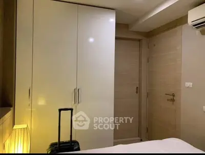 Modern bedroom with sleek wardrobe and ambient lighting, featuring a stylish suitcase for a touch of travel elegance.
