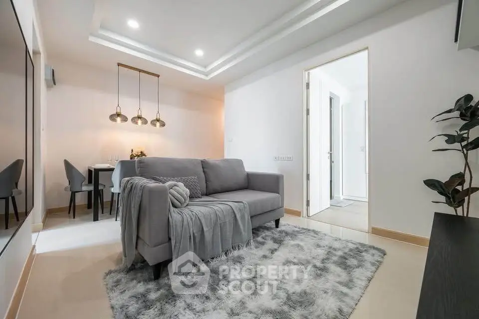 Modern living room with cozy gray sofa and elegant dining area in open layout apartment.