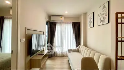 Modern living room with cozy sofa and wall-mounted TV, featuring elegant decor and natural light.