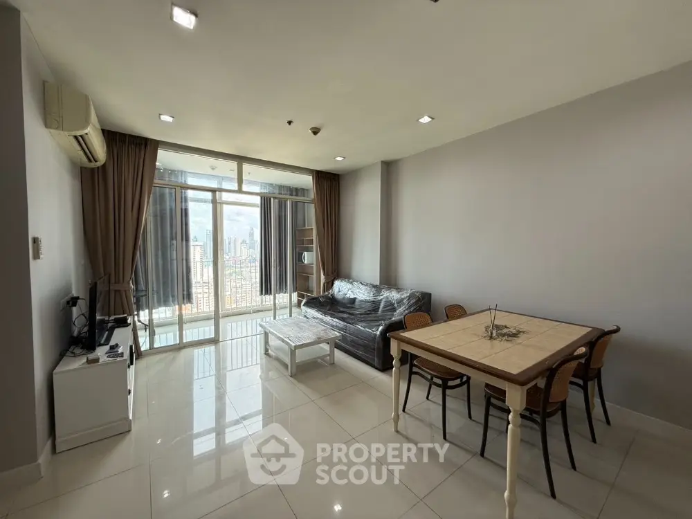 Spacious living room with city view and modern furnishings in high-rise apartment.