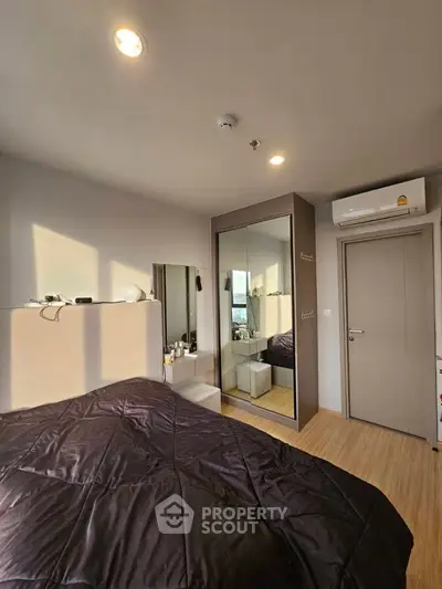 Cozy bedroom with modern decor and ample natural light, featuring a mirrored wardrobe and air conditioning.