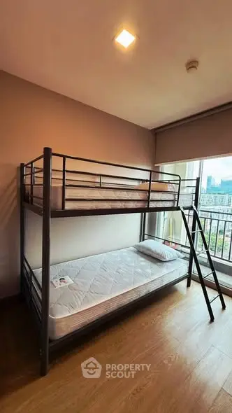 Modern bedroom with bunk bed and city view from window.