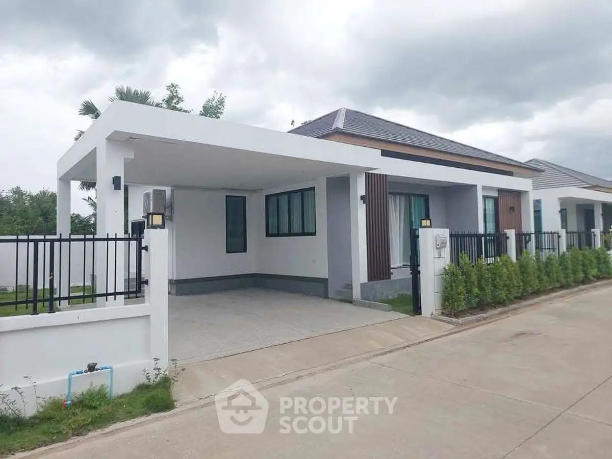Modern single-story house with sleek design and spacious driveway in a serene neighborhood.