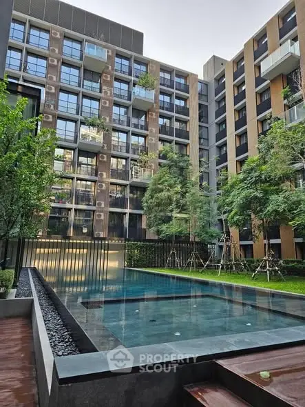 Modern apartment complex with a serene swimming pool and lush greenery