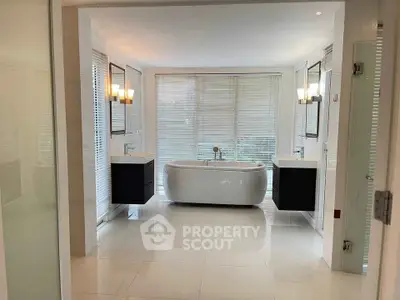 Luxurious modern bathroom with freestanding tub and dual vanities in elegant white decor.