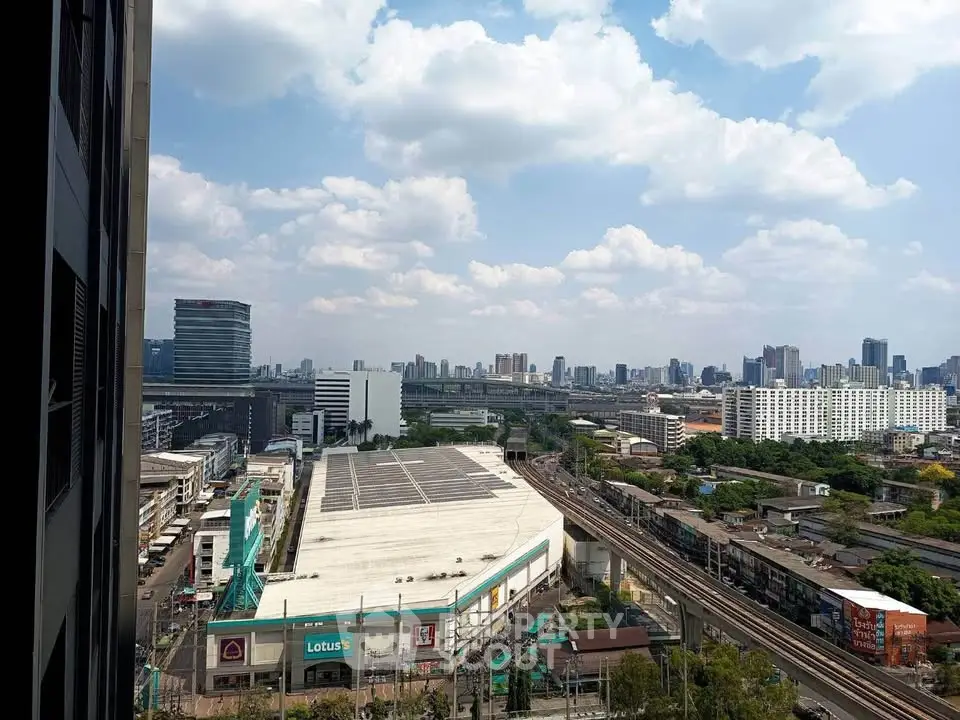 Stunning cityscape view from high-rise building showcasing urban skyline and railway tracks.