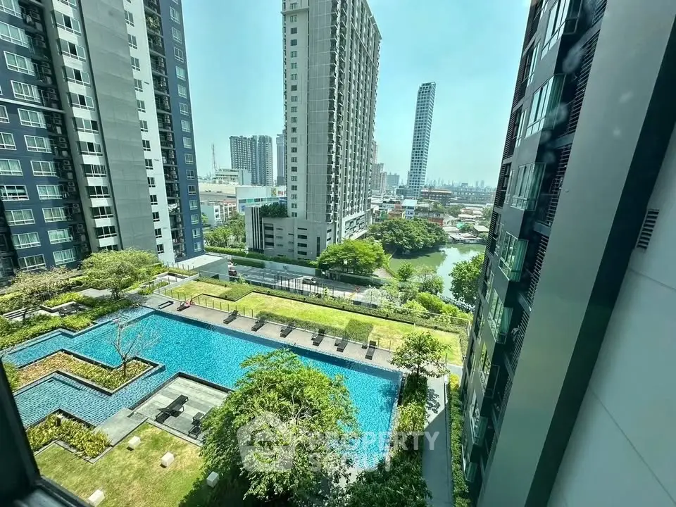 Stunning high-rise apartment view with pool and lush greenery in urban setting.
