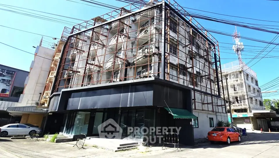 Modern commercial building with unique facade and ample parking space in urban setting.