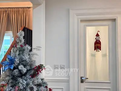 Elegant interior with festive Christmas decor and frosted tree in cozy living space.