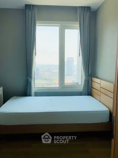 Bright bedroom with large window offering stunning city view in modern apartment.