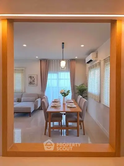 Modern dining room with elegant table setting and cozy living area, featuring large windows and stylish decor.