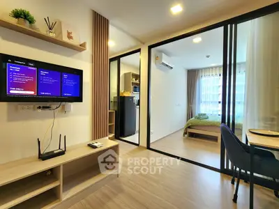 Modern open-plan living room with TV and view into cozy bedroom
