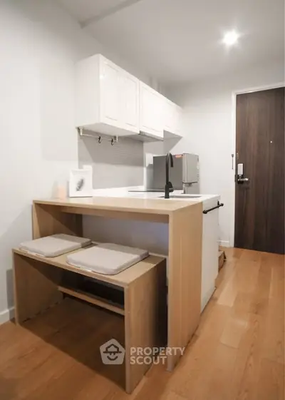 Modern kitchen with sleek design and wooden flooring, featuring a compact dining area and contemporary appliances.