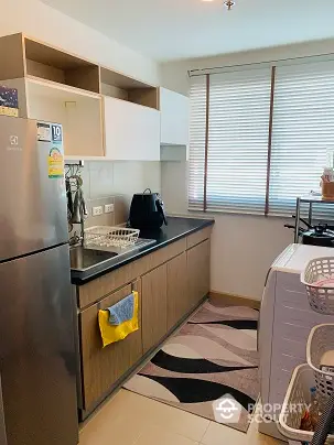 Modern kitchen with sleek cabinetry and appliances, featuring a washing machine and ample natural light.