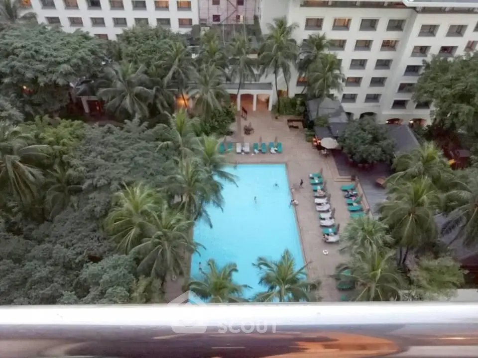 Luxurious apartment complex with a stunning pool view surrounded by lush greenery.