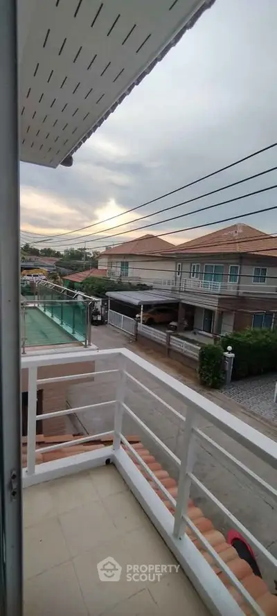 Charming suburban view from a cozy balcony overlooking residential street and houses.