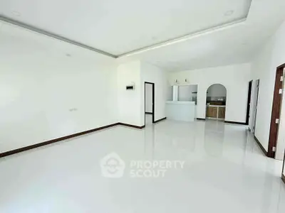 Spacious open-plan living room with modern kitchen and sleek white tiles