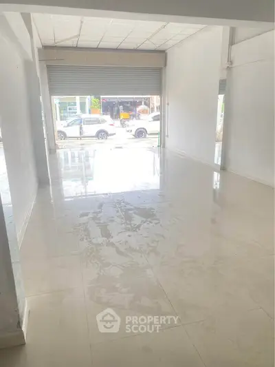 Spacious empty commercial space with large front windows and tiled flooring, ideal for retail or office use.