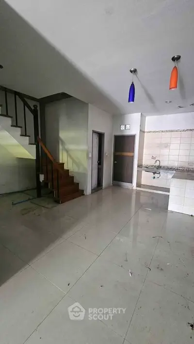 Spacious open-plan living area with modern staircase and kitchen, ideal for contemporary living.