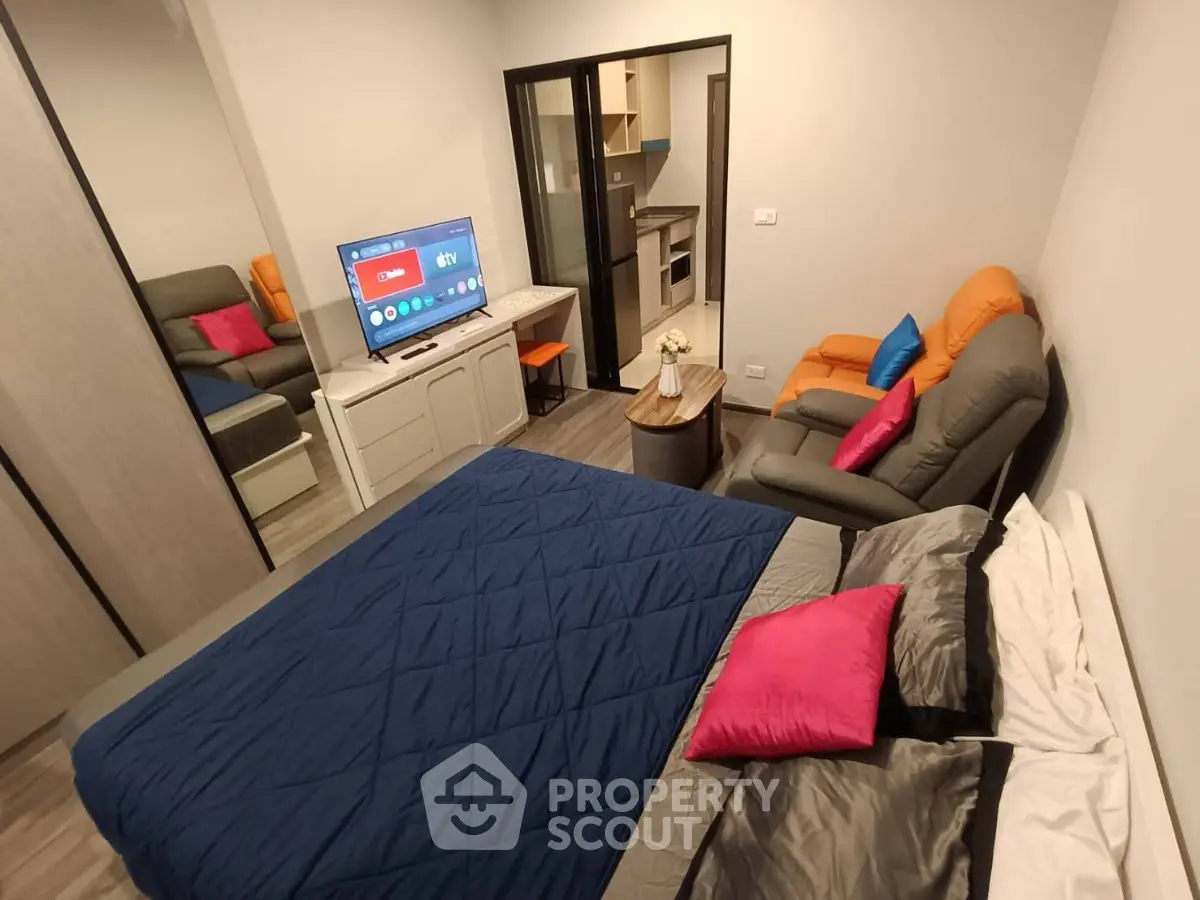 Modern studio apartment with cozy living area and smart TV, featuring a compact kitchen and stylish decor.