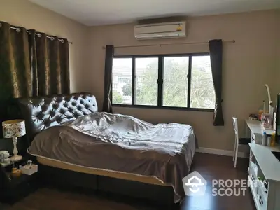 Spacious bedroom with large windows, elegant tufted headboard, and modern air conditioning unit, offering a comfortable and stylish living space.