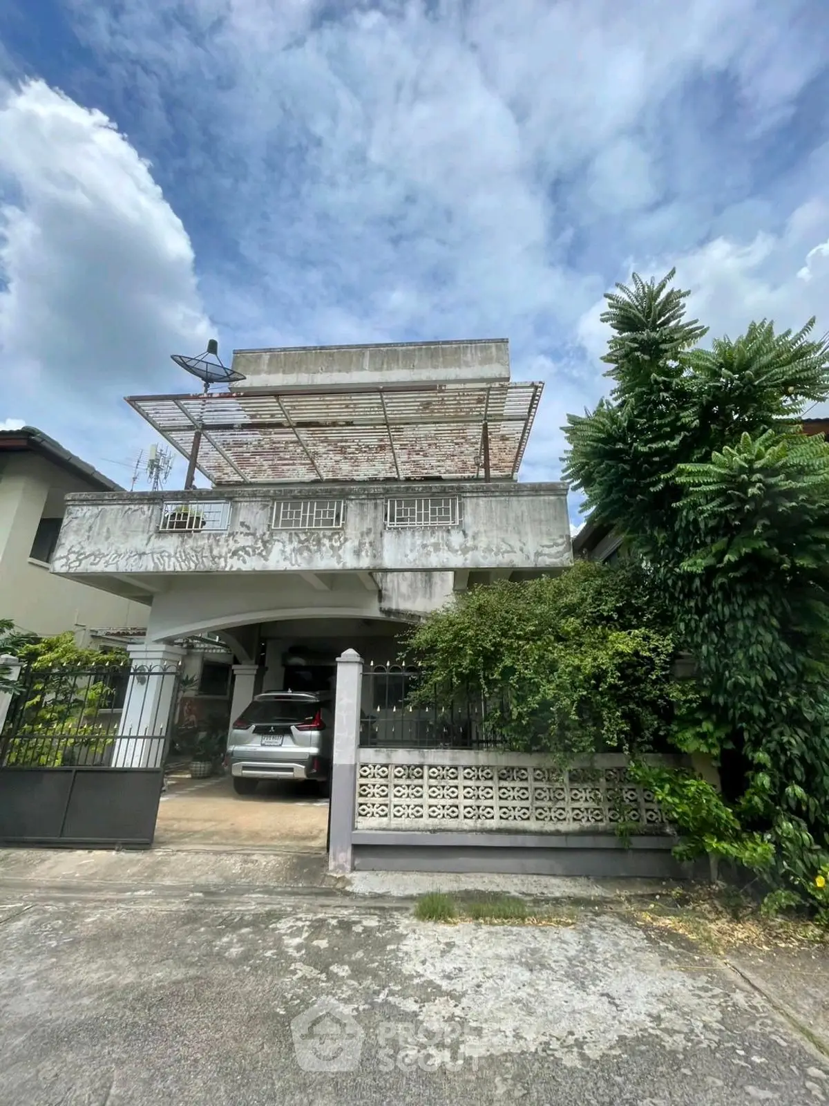 Charming two-story house with carport and lush greenery, perfect for family living.