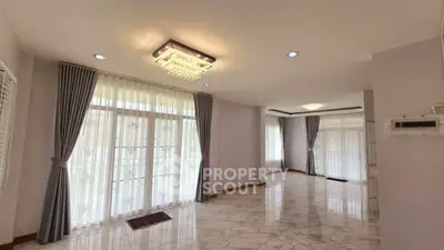 Spacious and elegant living room with large windows and modern lighting.